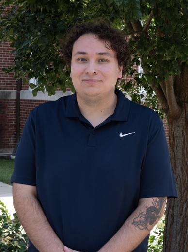 man in navy blue polo shirt stands in front of tree