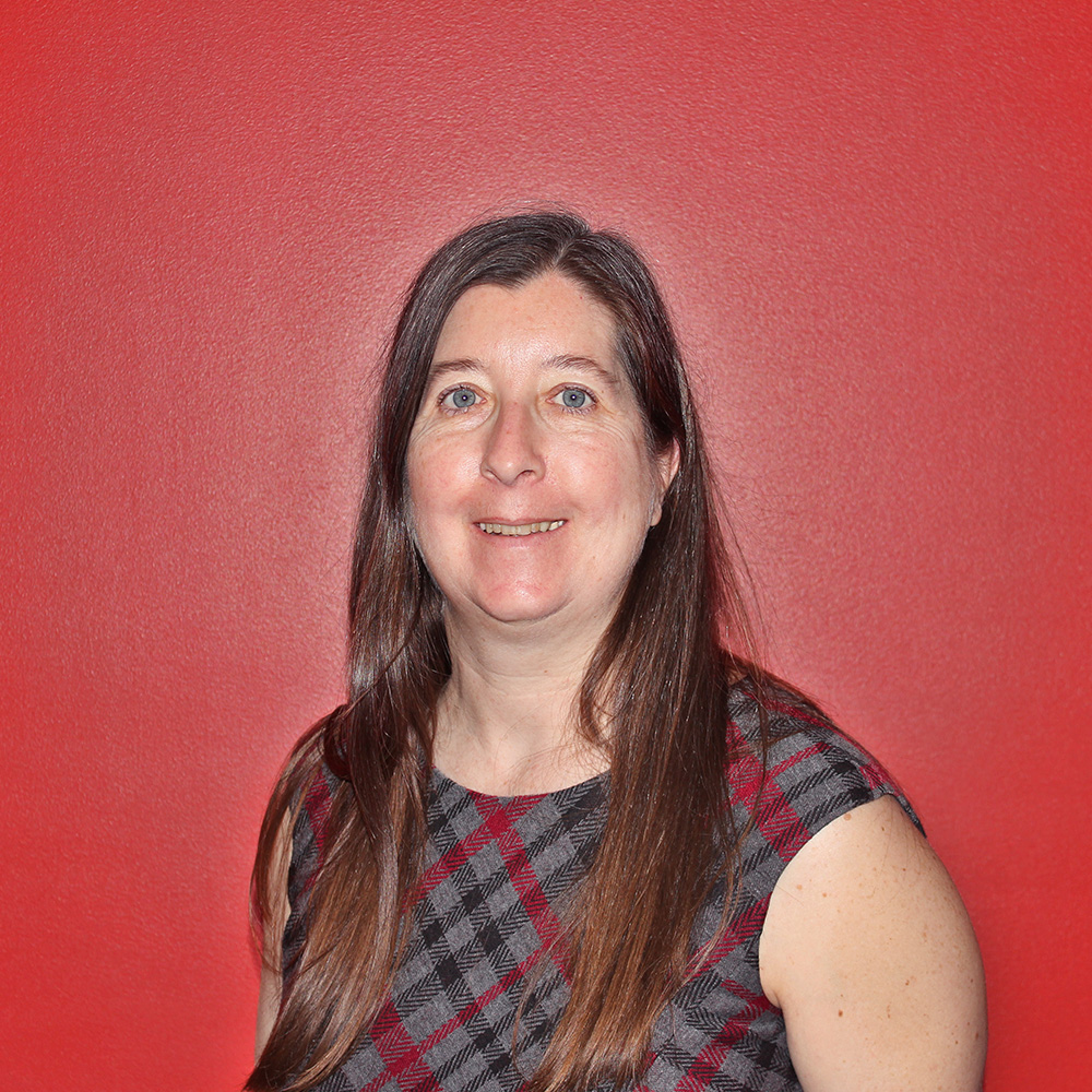 woman with long brown hair in black shirt with building blurred in background